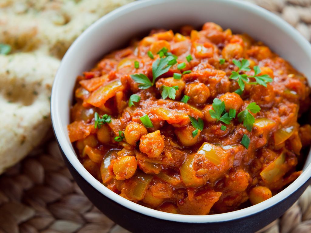 In einer Schale wird Chana Masala serviert - Kichererbsen in einer Soße auf Tomatenbasis.