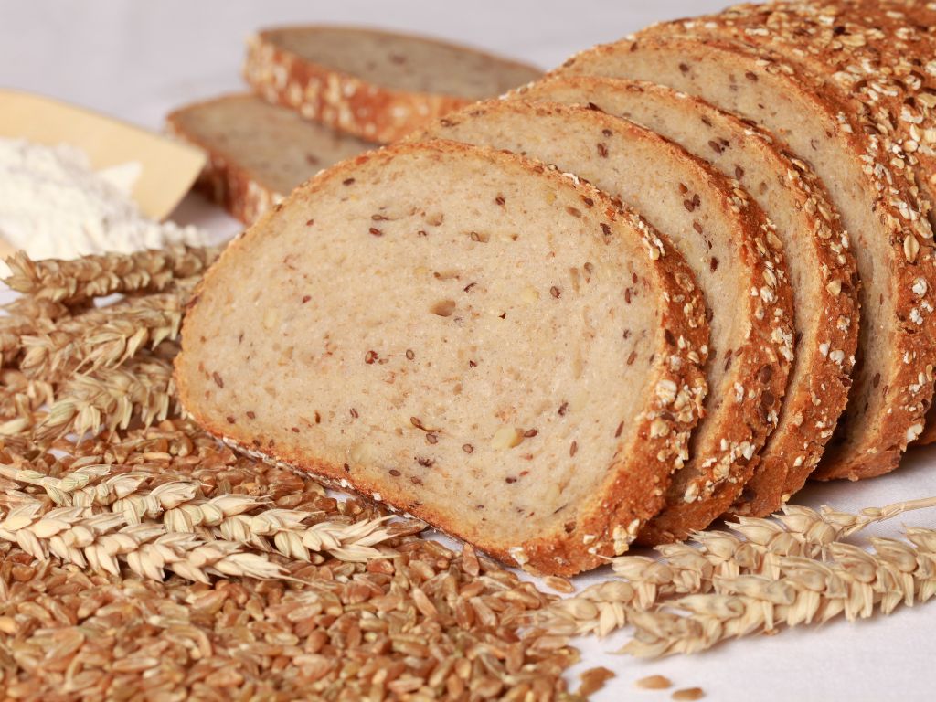 Ein in Scheiben geschnittenes Weizenbrot liegt auf einem weißen Tuch.