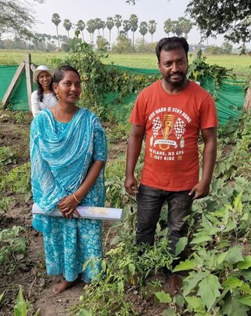 Sovyanya Soujanaya and her husband are standing in their garden. Sovyanya is holding a map in her hand.