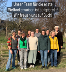 Eine Guppe von 10 Personen steht auf einer Wiese und lächelt in die Kamera.