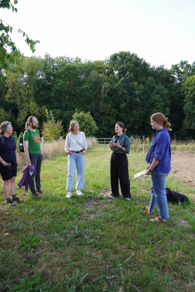 Five people stand in a semi-circle on the Global Field, the two Dortmund women tell their stories.  
