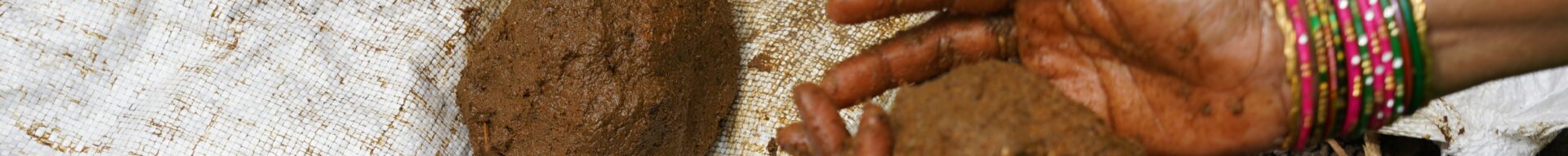 Die Hände einer Frau formen eine Kugel aus Erde.