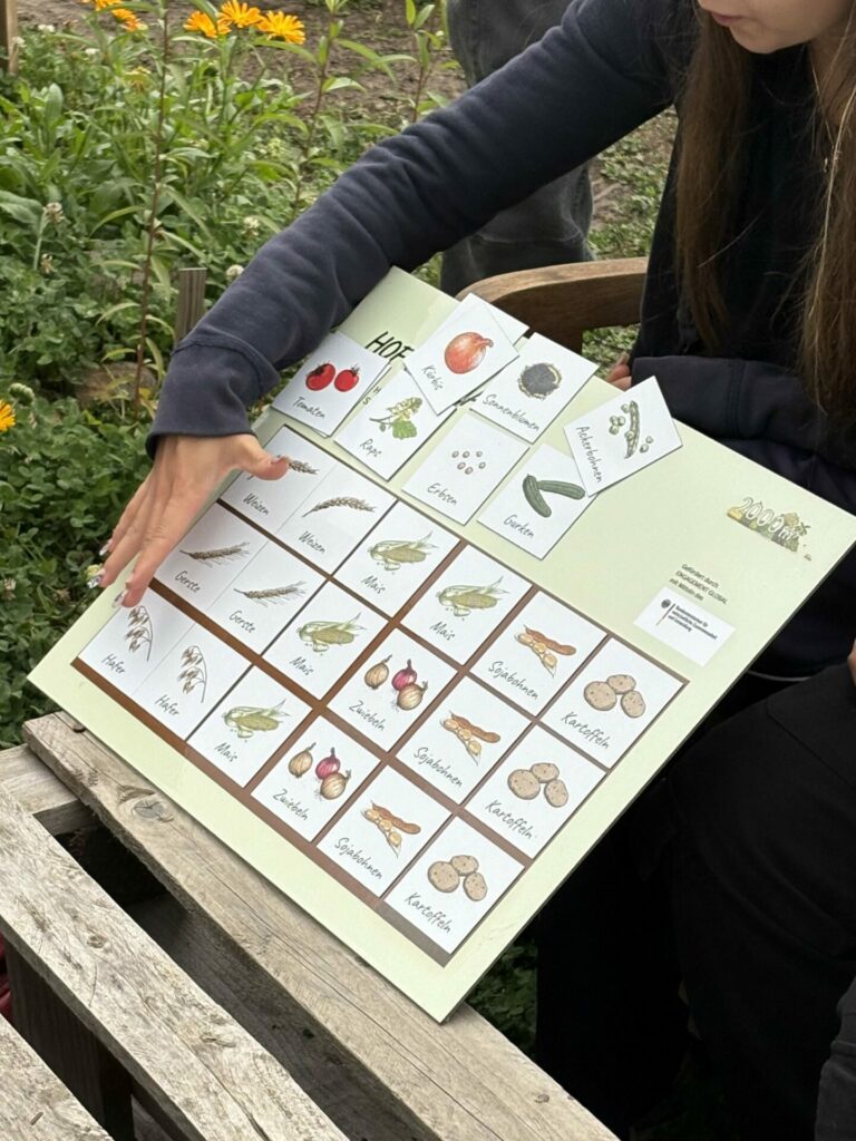 Eine Teilnehmerin hält eine Magnettafel hoch, auf der sie ihren eignen Hof mit magnetischen Tafeln angebaut hat.