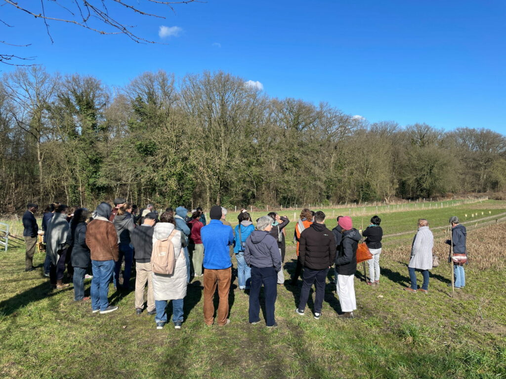 A large group of adults stands in front of the Global Field in Dortmund.  