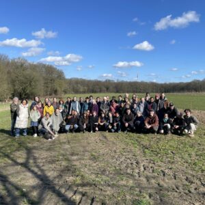 Eine große Gruppe steht für ein Gruppenbild auf einem Acker.