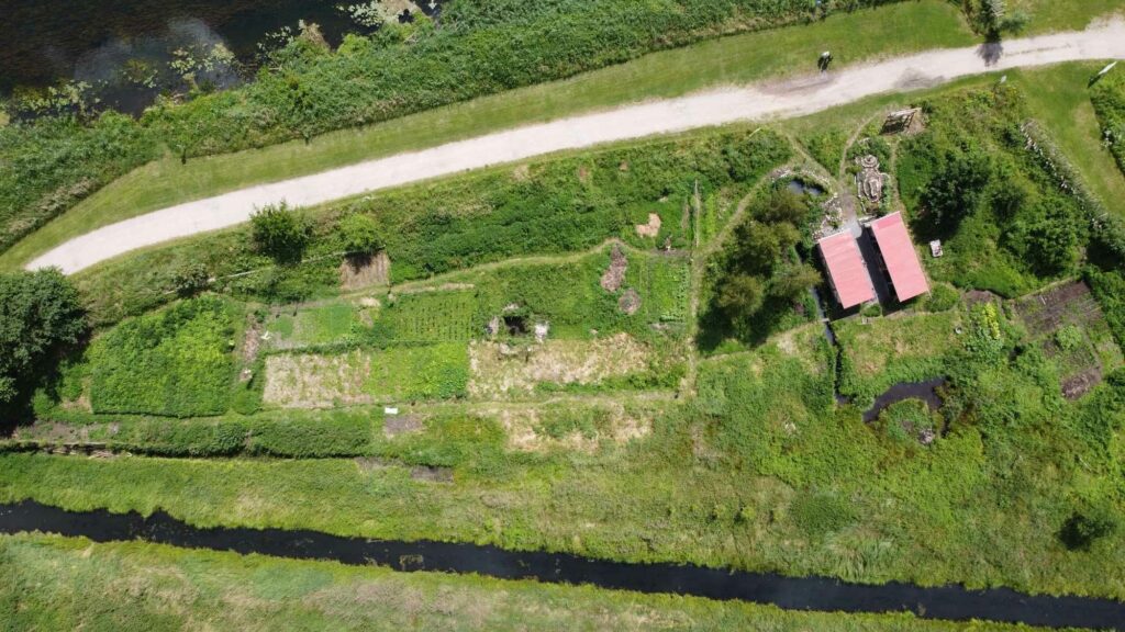 Aus der Luft ist der Weltacker Ukranenland zu sehen. Oben auf dem Bild ist ein Fluss und unten ein Bach zu erkennen, dazwischen erstreckt sich neben einem Weg der Weltacker.