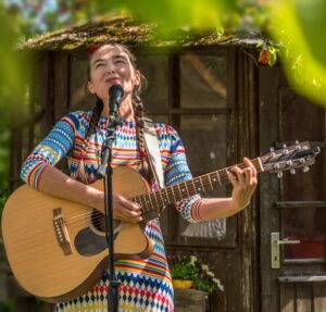 Die Liedermacherin Irene Mazza am Musizieren mit akustischer Gitarre und Mikrophon